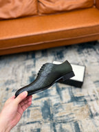 Black crocodile-embossed lace-up dress shoe held up, side and heel view
