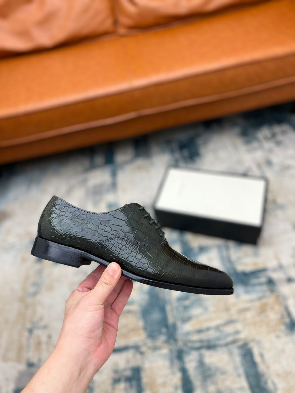 Black crocodile-embossed lace-up dress shoe held up, low profile sole