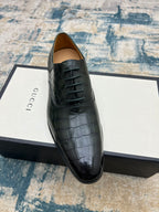 Black crocodile-embossed lace-up dress shoe on box, front angled view