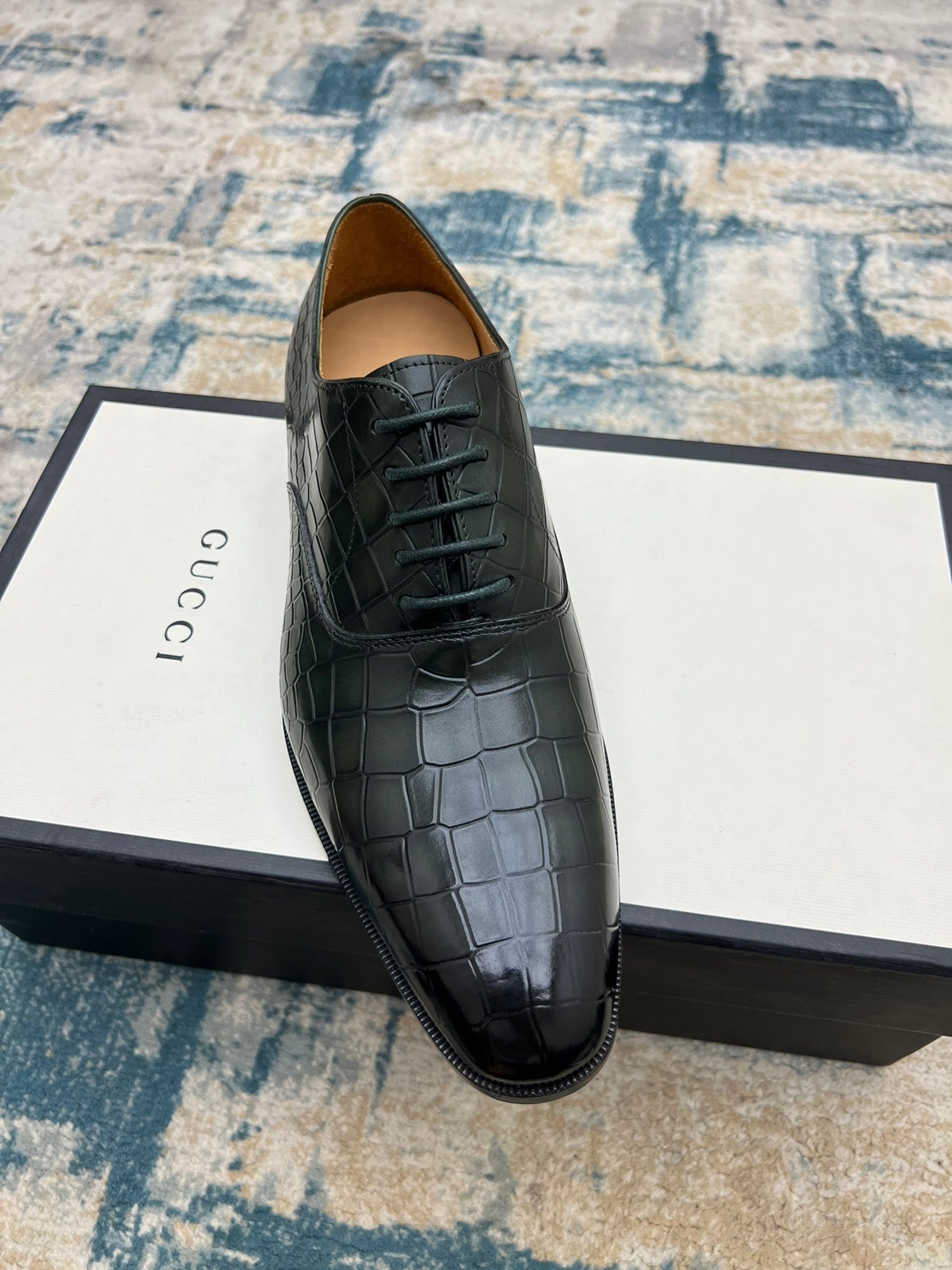 Black crocodile-embossed lace-up dress shoe on box, front angled view