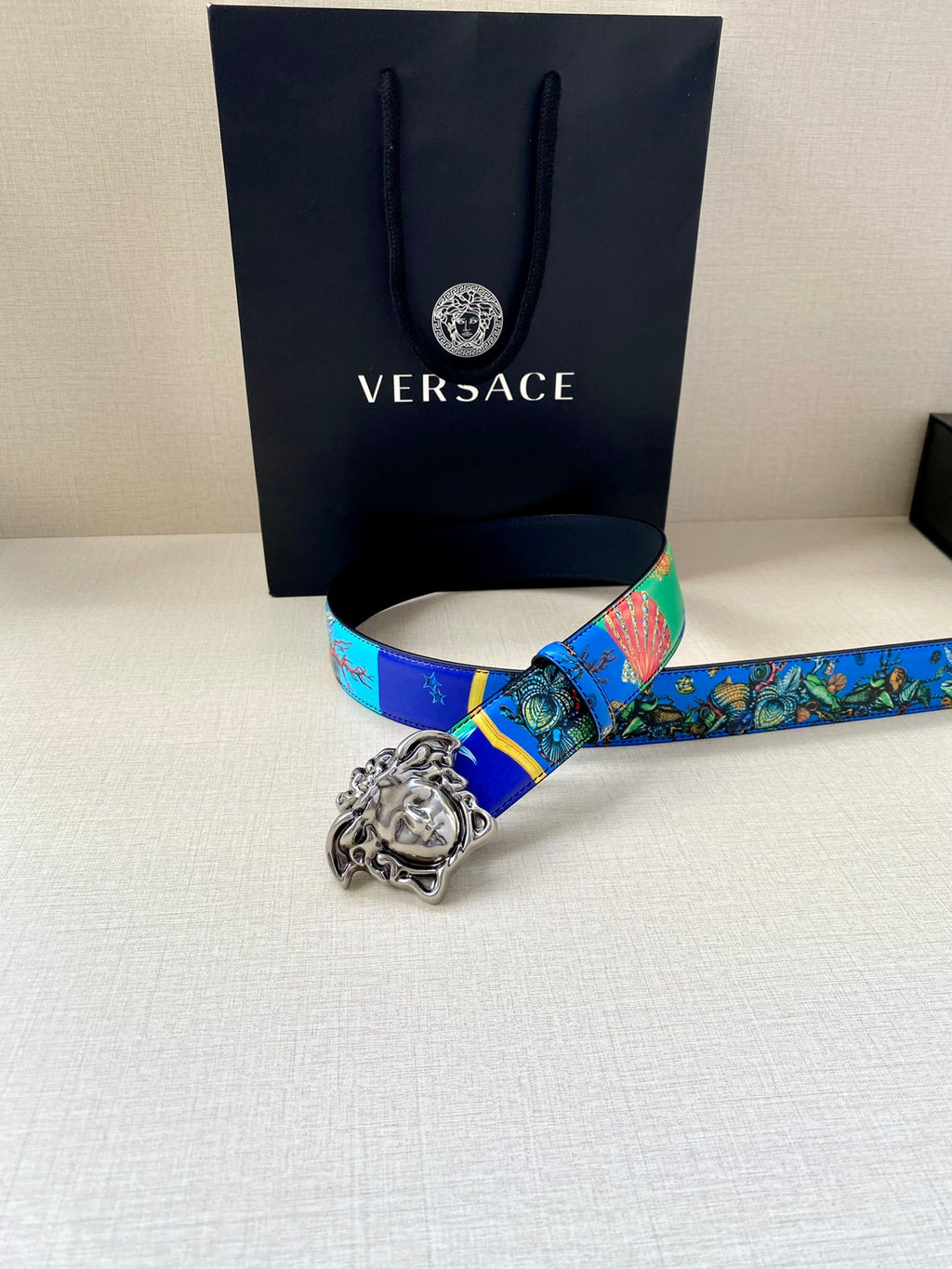 Versace belt lying flat with blue printed strap and silver-tone Medusa buckle