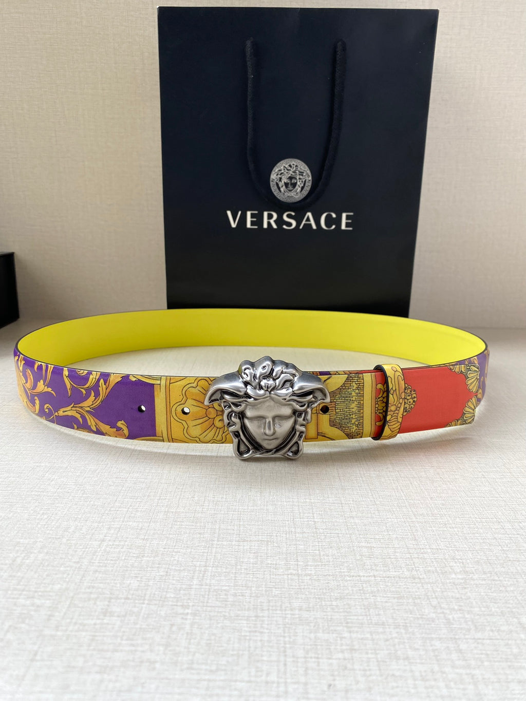 Versace belt flat lay with silver Medusa buckle and yellow baroque print strap