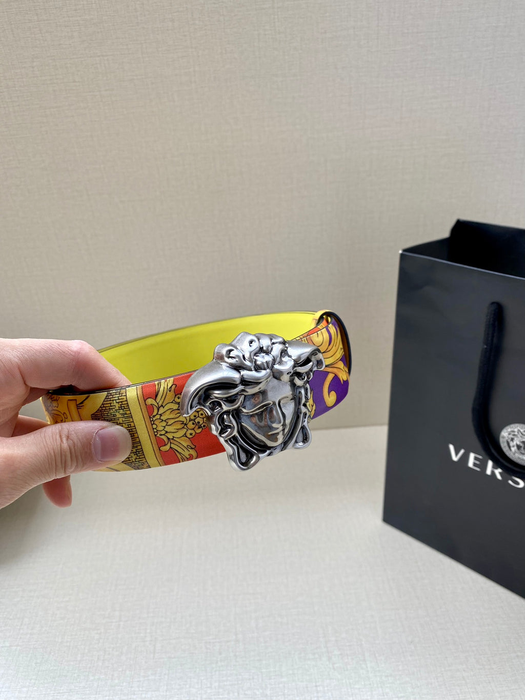 Versace belt close-up with silver Medusa buckle on yellow patterned strap end