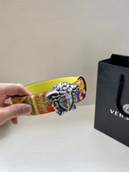 Versace belt close-up with silver Medusa buckle on yellow patterned strap end