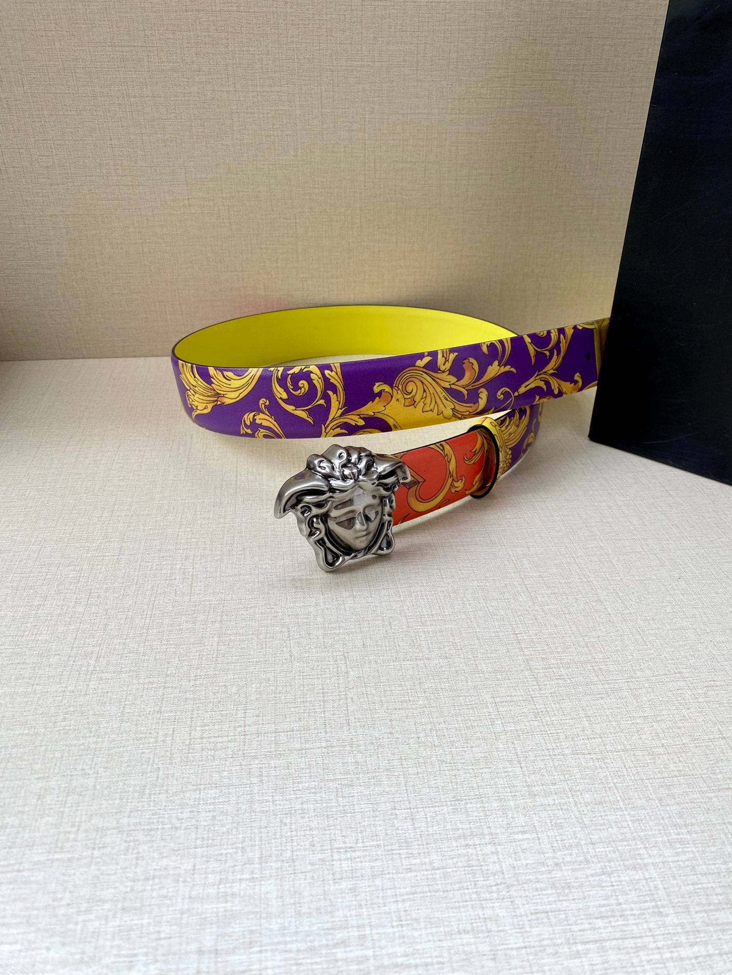 Versace belt on table with silver Medusa buckle and purple yellow baroque strap
