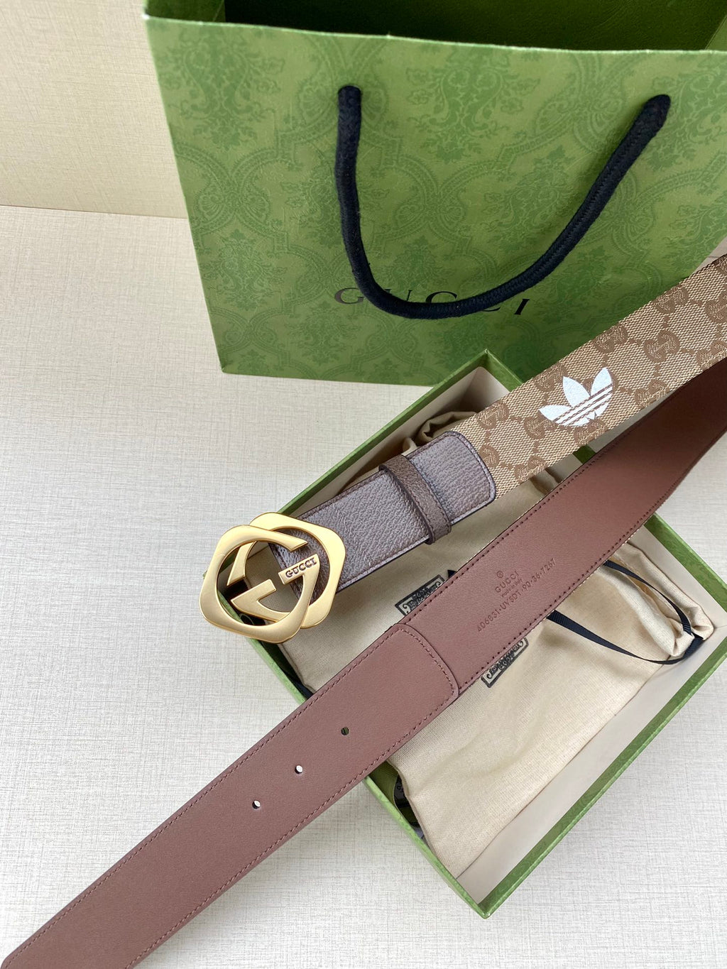 Gucci belt with beige monogram lining, dark leather strap, and gold-tone double G buckle