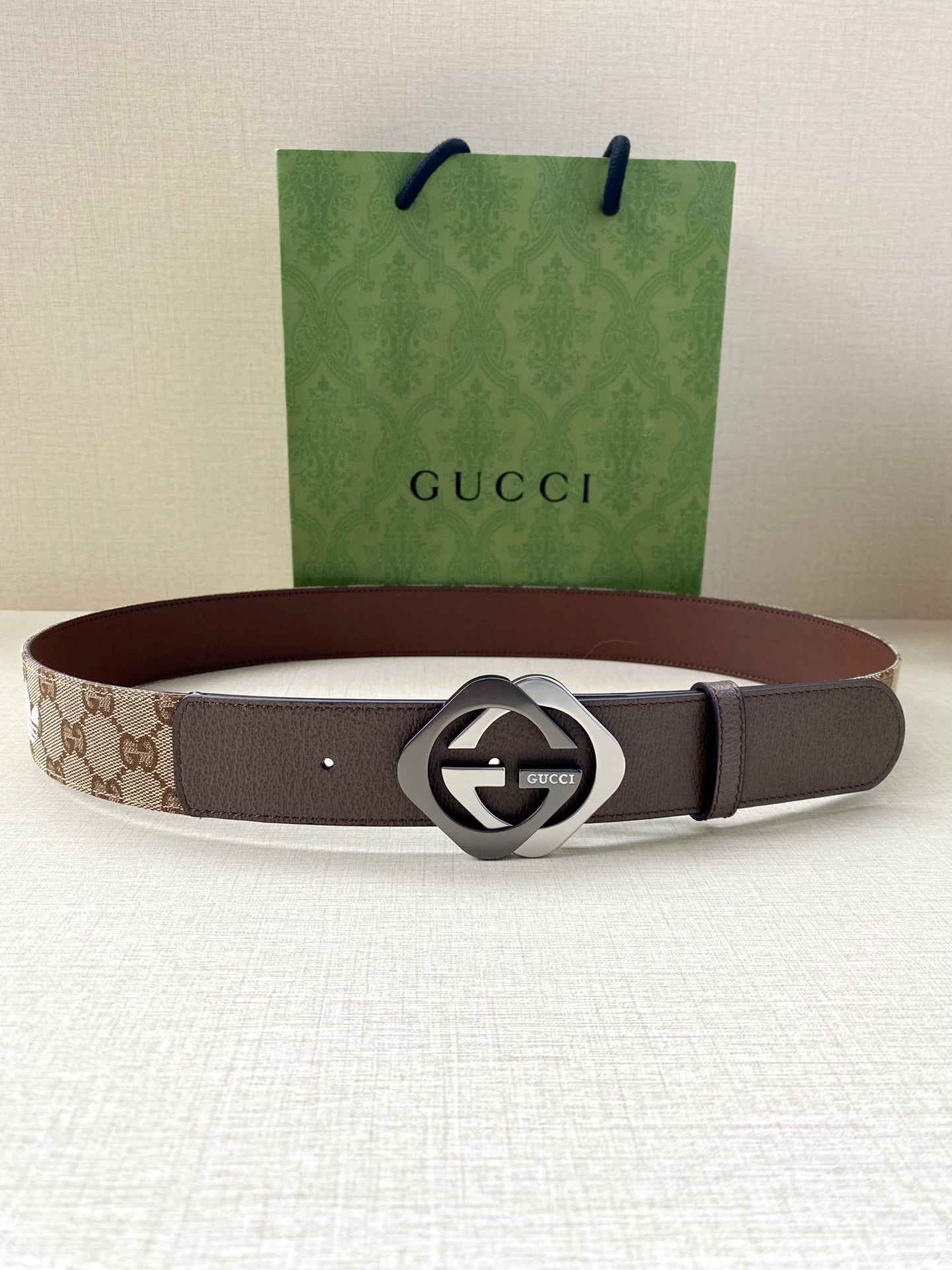 Gucci belt flat lay with brown leather strap and circular GG buckle
