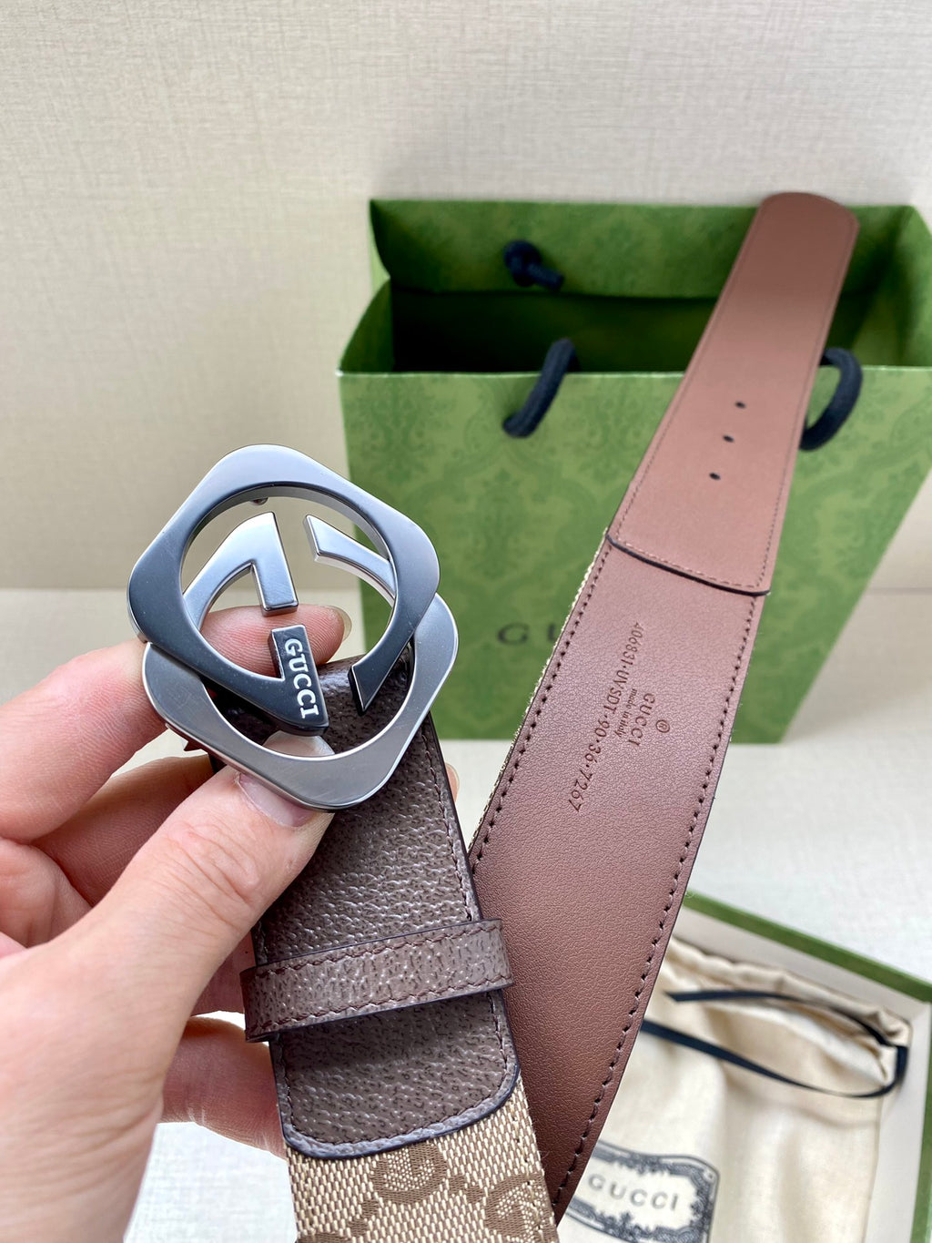 Gucci belt buckle close-up with dark strap and brown leather back