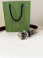 Gucci belt with dark strap and gold-tone circular logo buckle, monogram panel