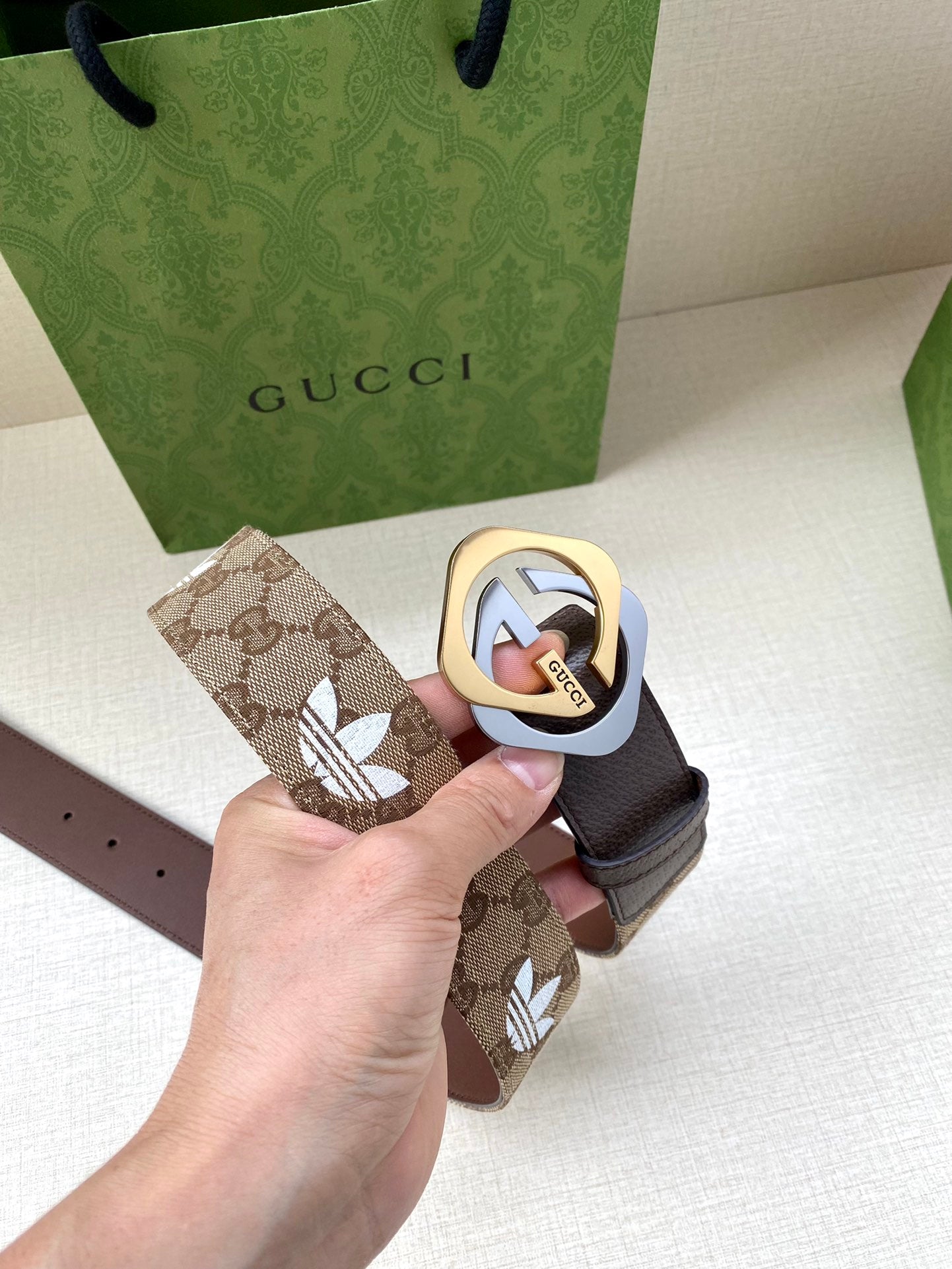 Gucci belt with dark strap and patterned beige end tab, circular logo buckle
