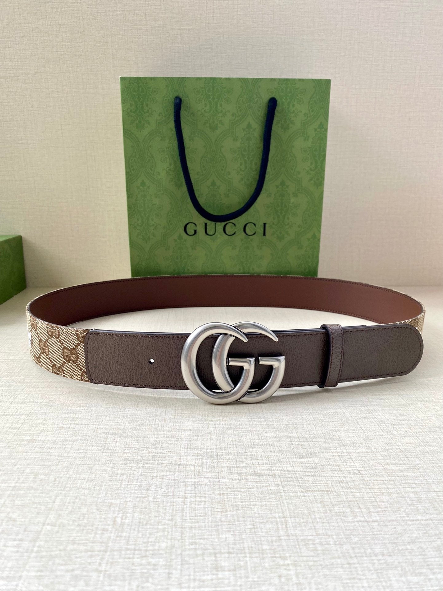 Gucci belt brown strap with GG monogram and silver double-G buckle, laid flat