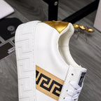 Side view of white leather sneaker with gold heel lining and gold logo band