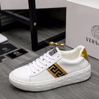 White leather low-top sneakers with gold logo panel and white textured outsole