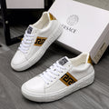 White low-top leather sneakers with gold logo stripe and gold heel accent
