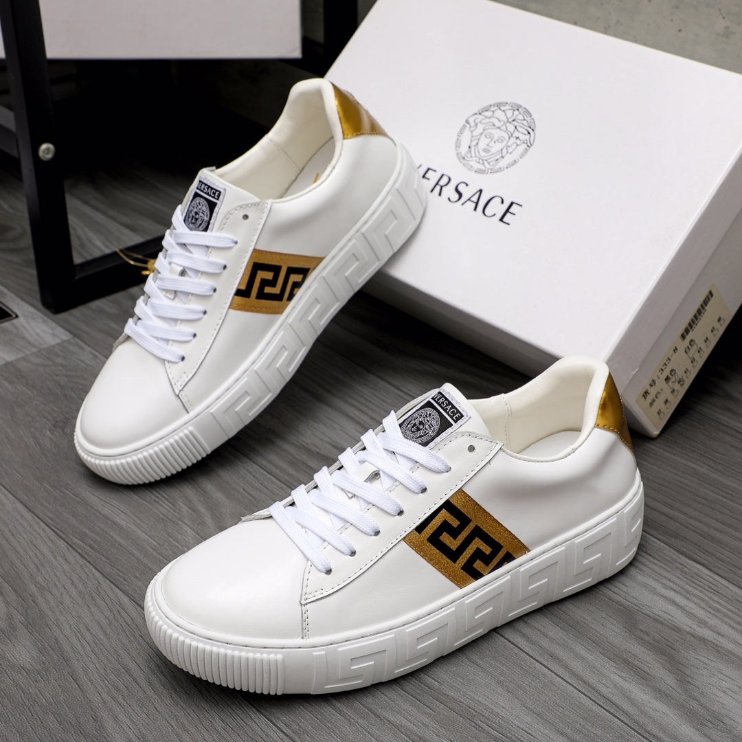 White low-top leather sneakers with gold logo stripe and gold heel accent