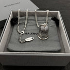 Silver-tone chain necklace with mesh bell pendant and small oval logo tag