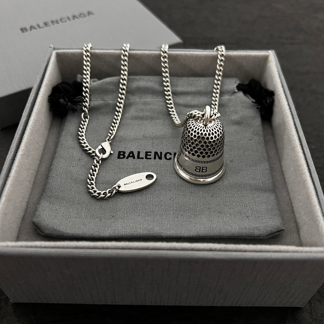 Silver-tone chain necklace with mesh bell pendant and small oval logo tag