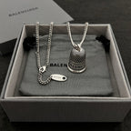 Silver-tone chain necklace set with mesh bell pendant and small oval logo tag