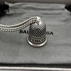 Close-up: silver mesh bell pendant on chain with logo band and 8B label