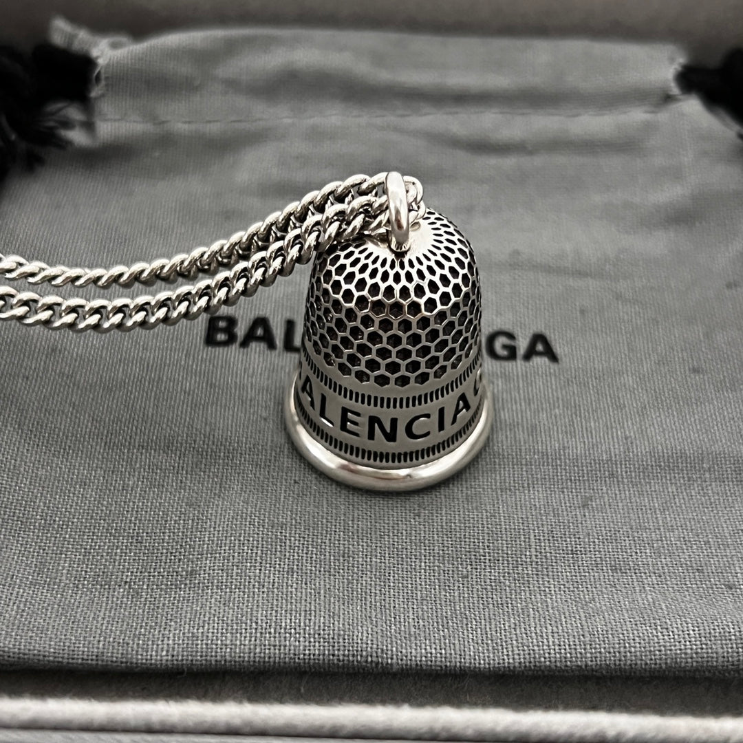 Close-up: silver mesh bell pendant on chain with logo band and 8B label