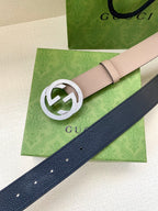 Gucci belt with light taupe strap and silver G logo buckle over dark blue strap
