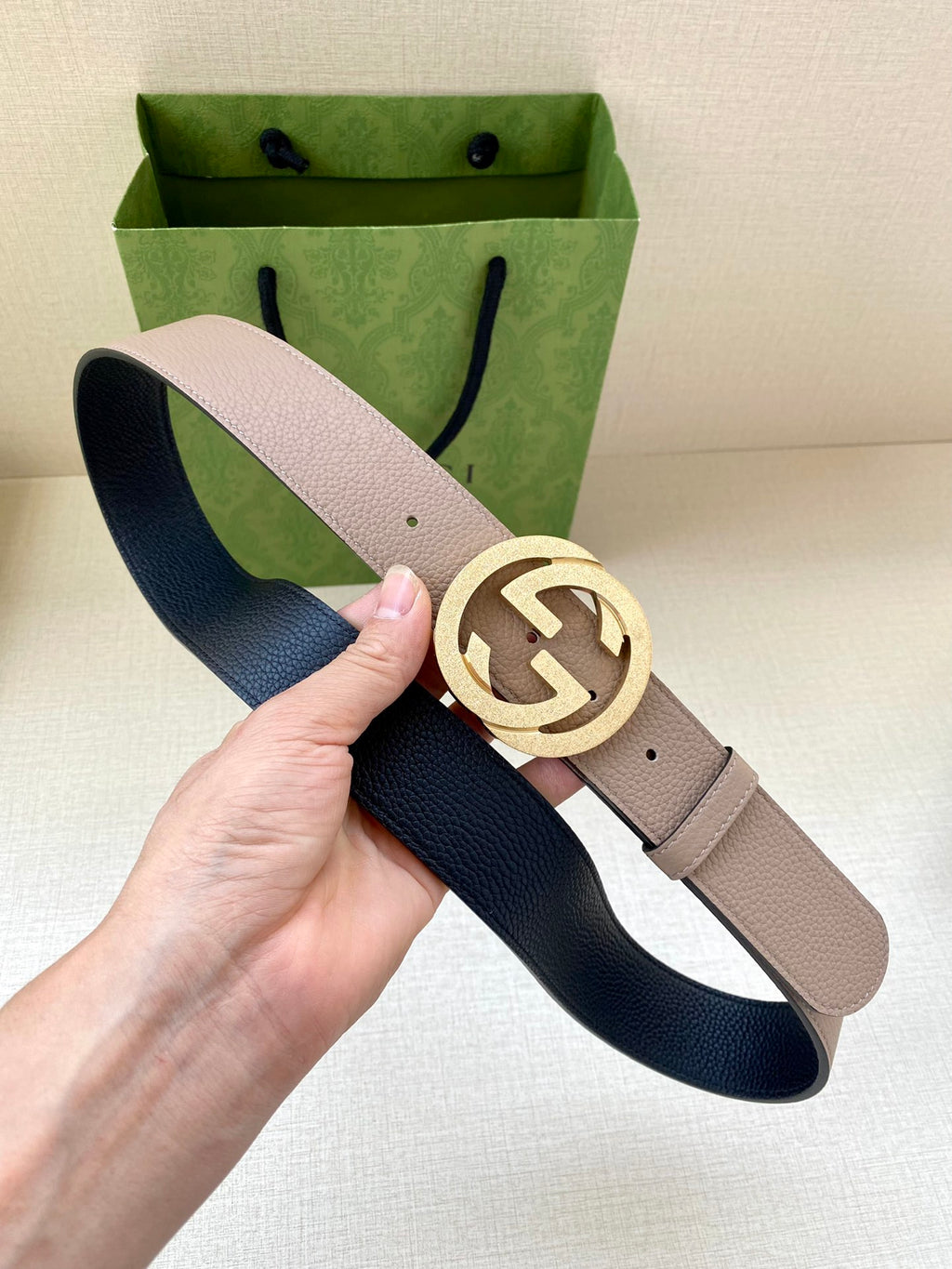 Gucci belt taupe strap with gold-toned G buckle; dark blue underside visible