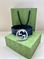 Navy leather belt with round silver logo buckle resting on box