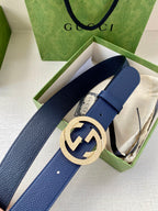 Navy leather belt with round gold logo buckle in open gift box