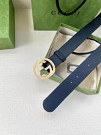 Navy leather belt with round gold GG buckle across gift box
