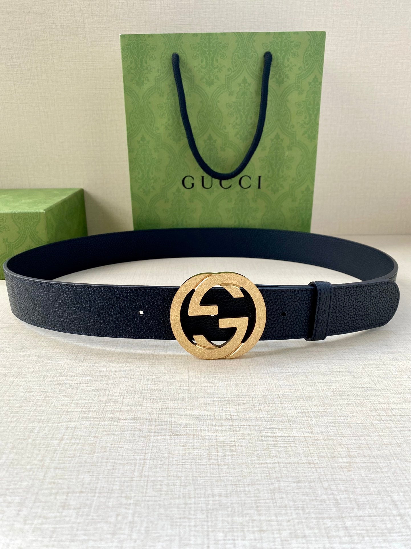 Navy leather belt with round gold GG buckle and textured strap