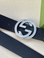 Navy leather belt close-up with round silver GG buckle and pebble texture
