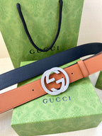 Gucci belt with navy and tan straps and silver GG buckle, angled