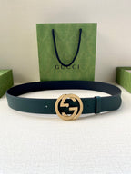 Teal leather belt with gold-tone interlocking logo buckle, laid flat