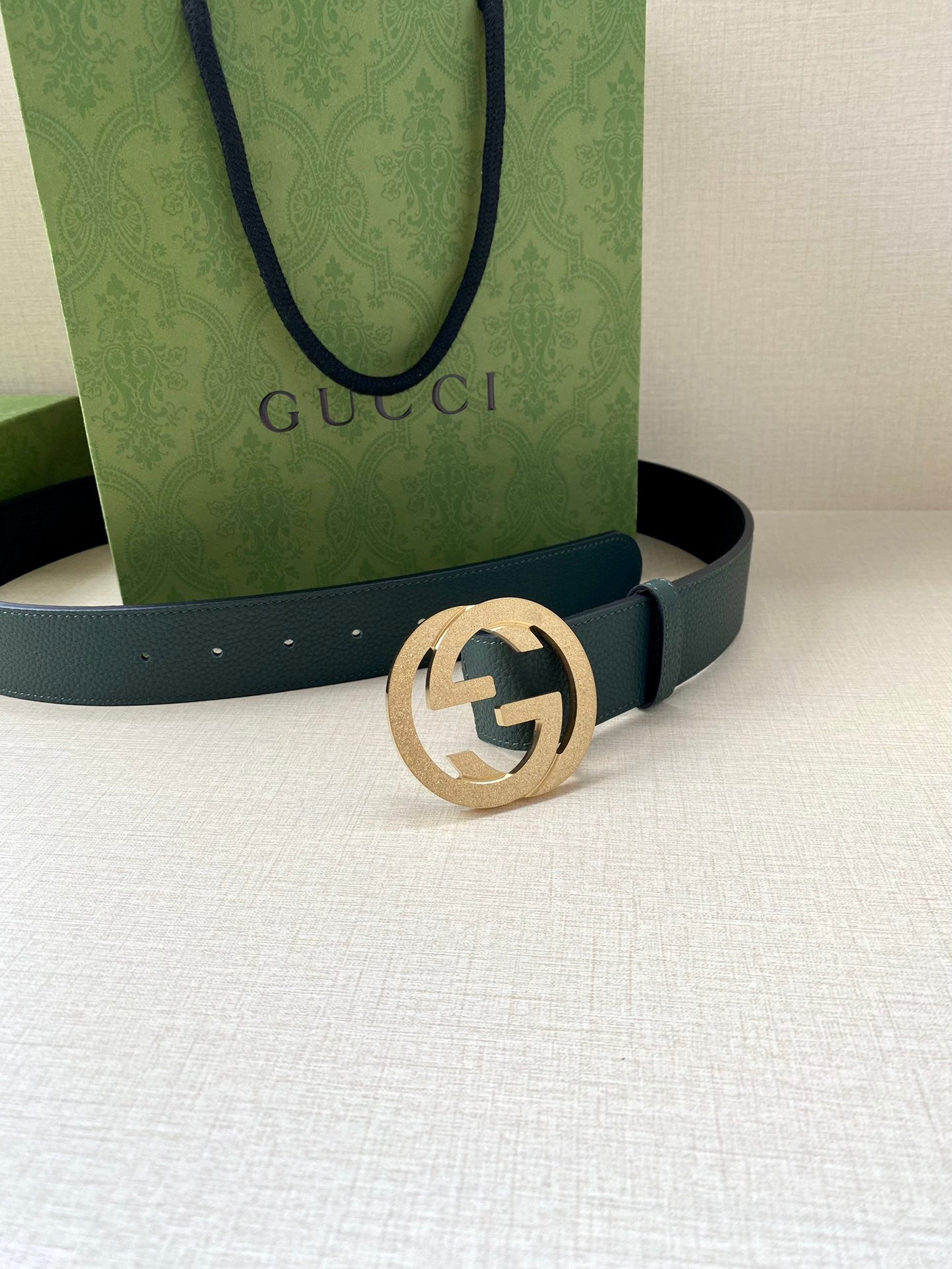 Teal leather belt with gold-tone interlocking logo buckle, front view