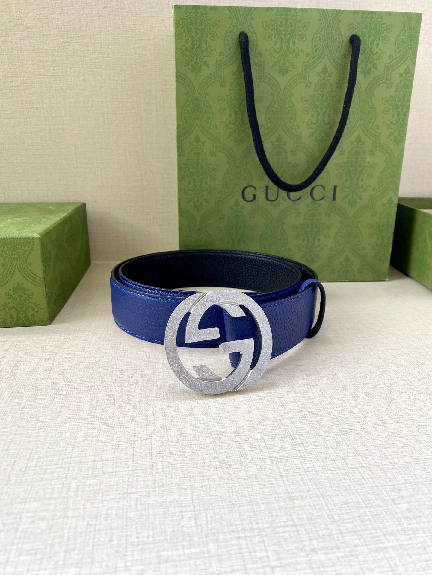 Gucci belt with blue strap and silver-tone GG buckle, laid flat