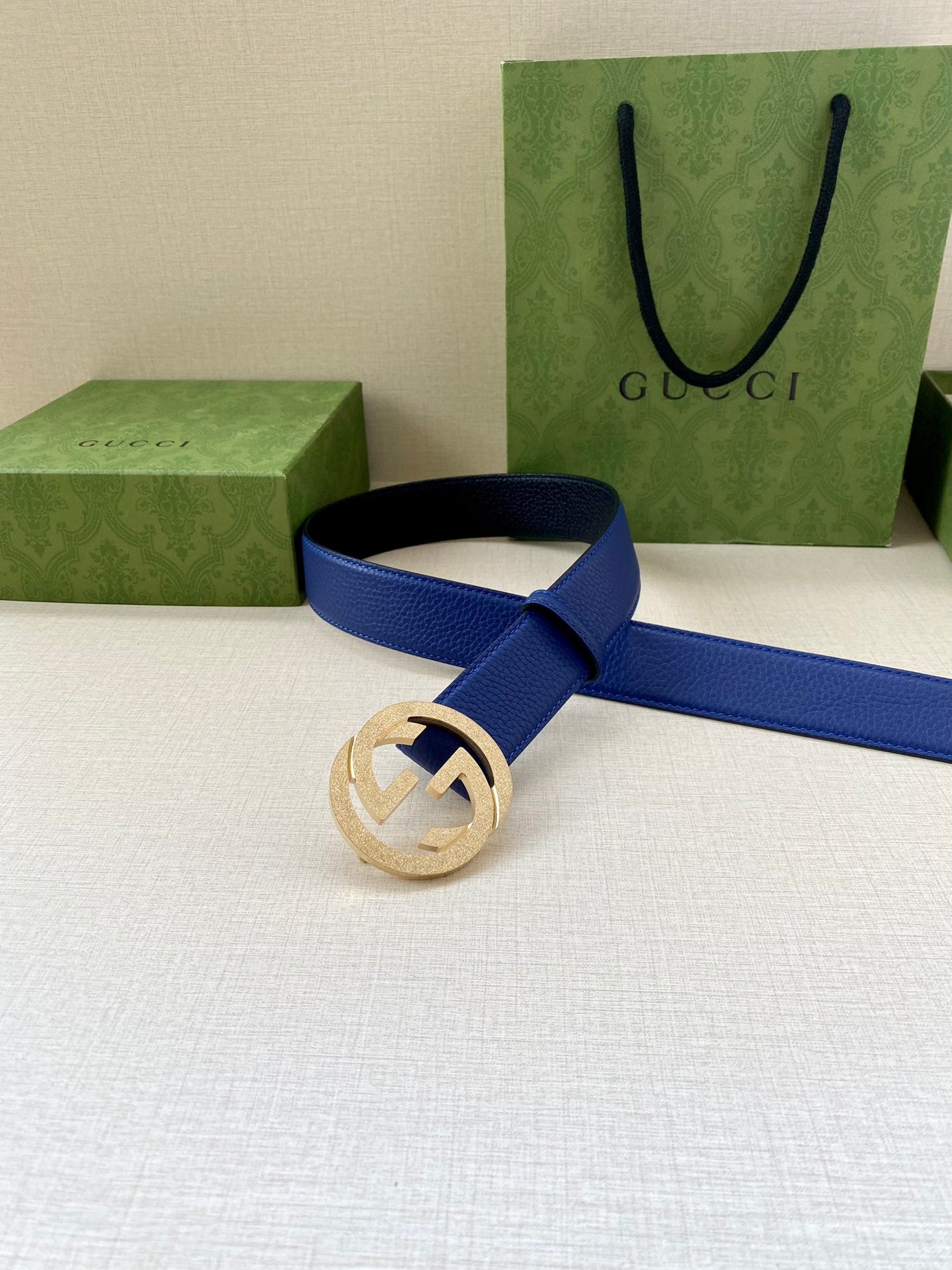 Gucci belt with blue strap and gold-toned GG buckle on a dark belt loop