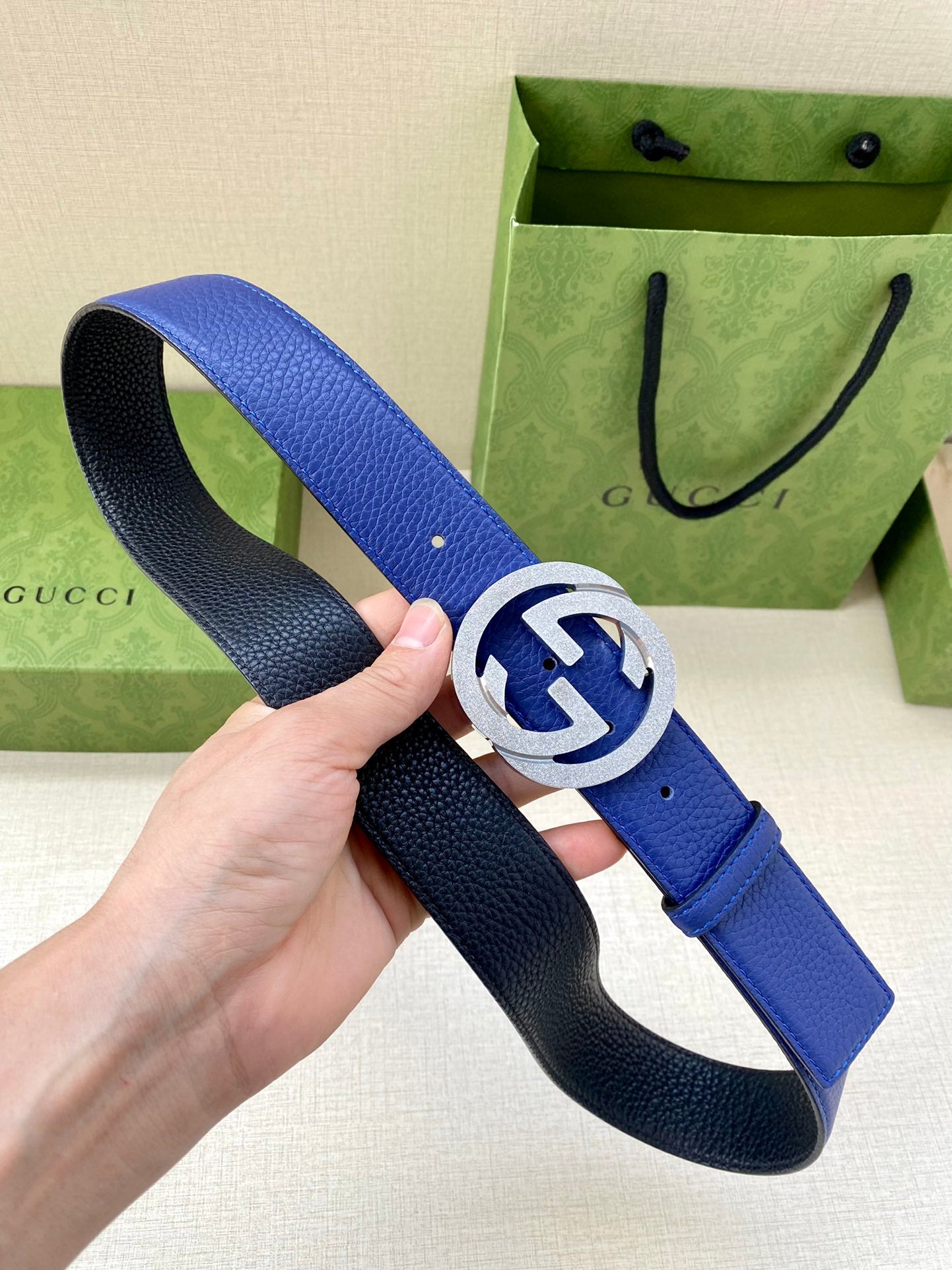 Gucci belt with blue leather strap and gold-toned GG buckle, shown at an angle