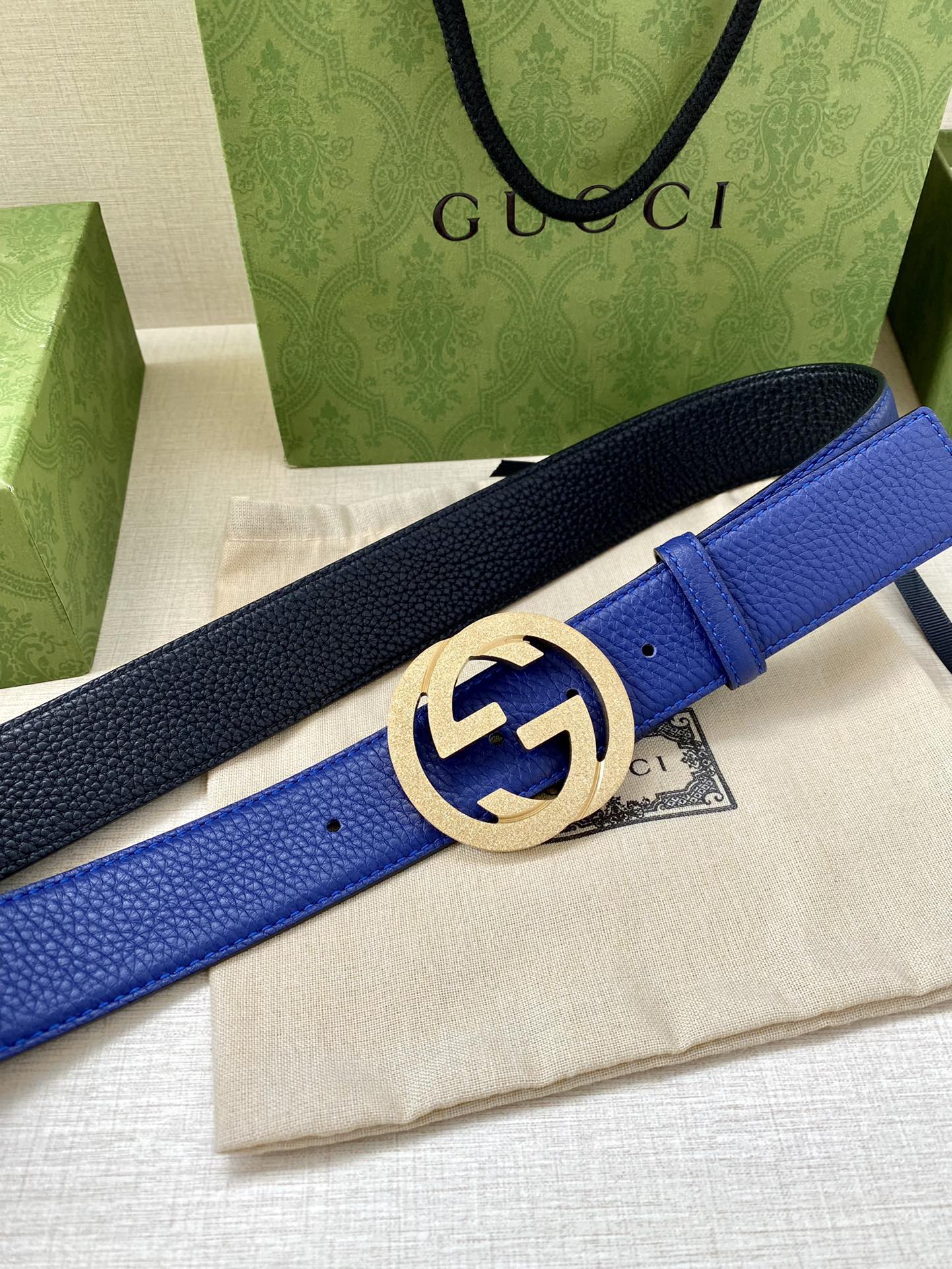 Gucci belt with blue and dark navy strap, featuring a gold-toned GG buckle