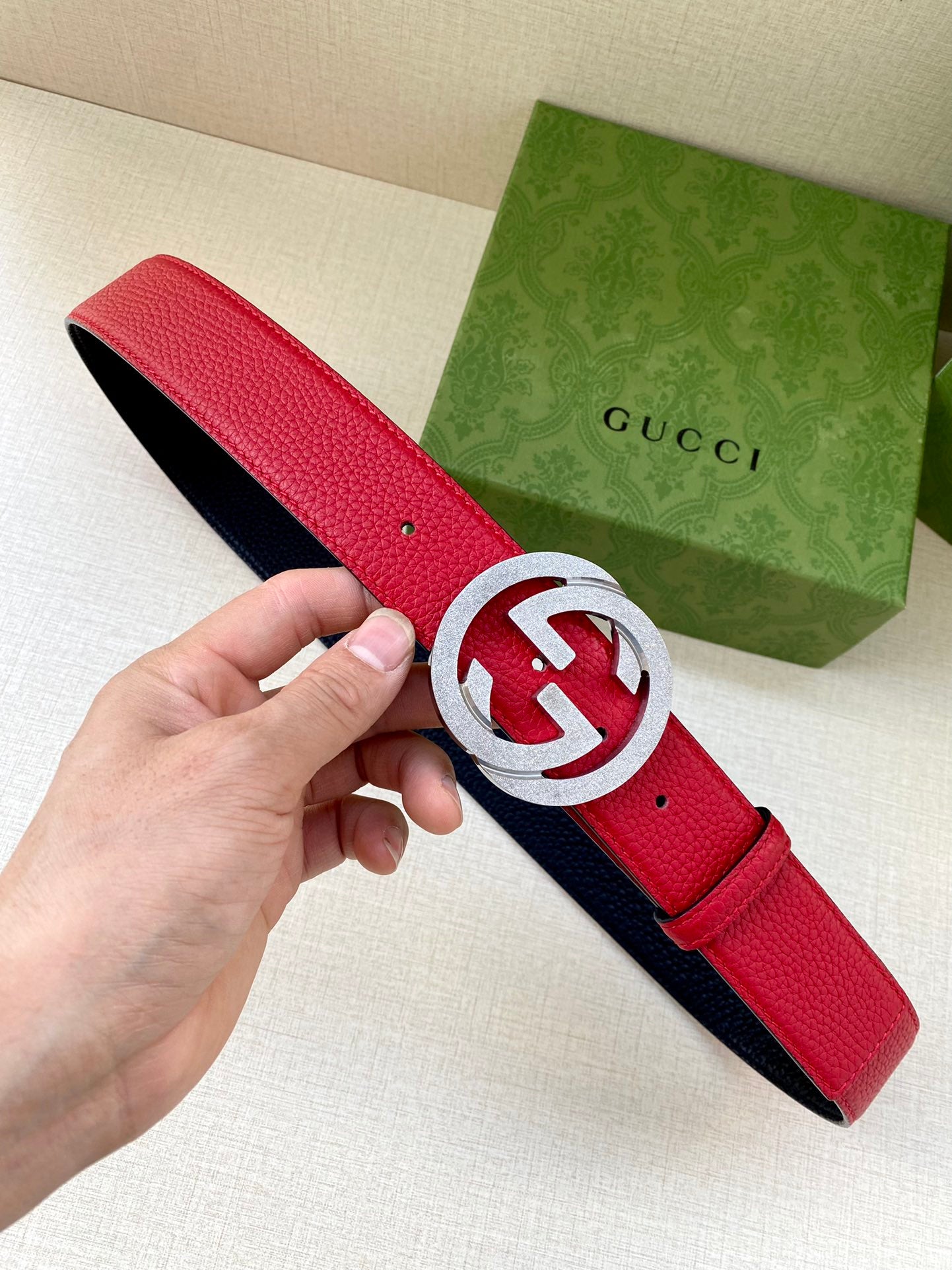 Red leather belt with interlocking G buckle in silver-tone, navy underside visible