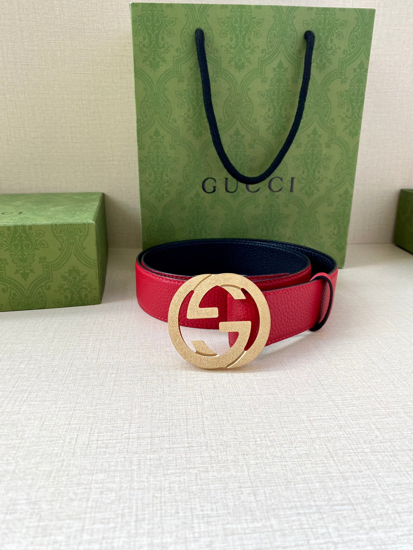 Red leather belt with gold-tone interlocking G buckle and navy underside