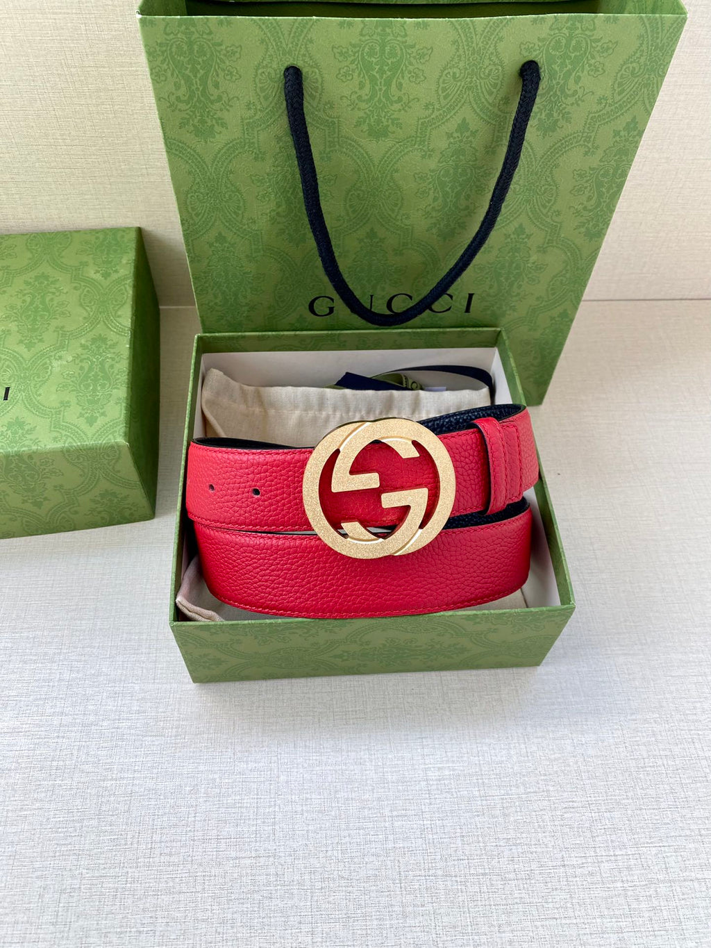 Red leather belt with gold-tone interlocking G buckle, set in a box