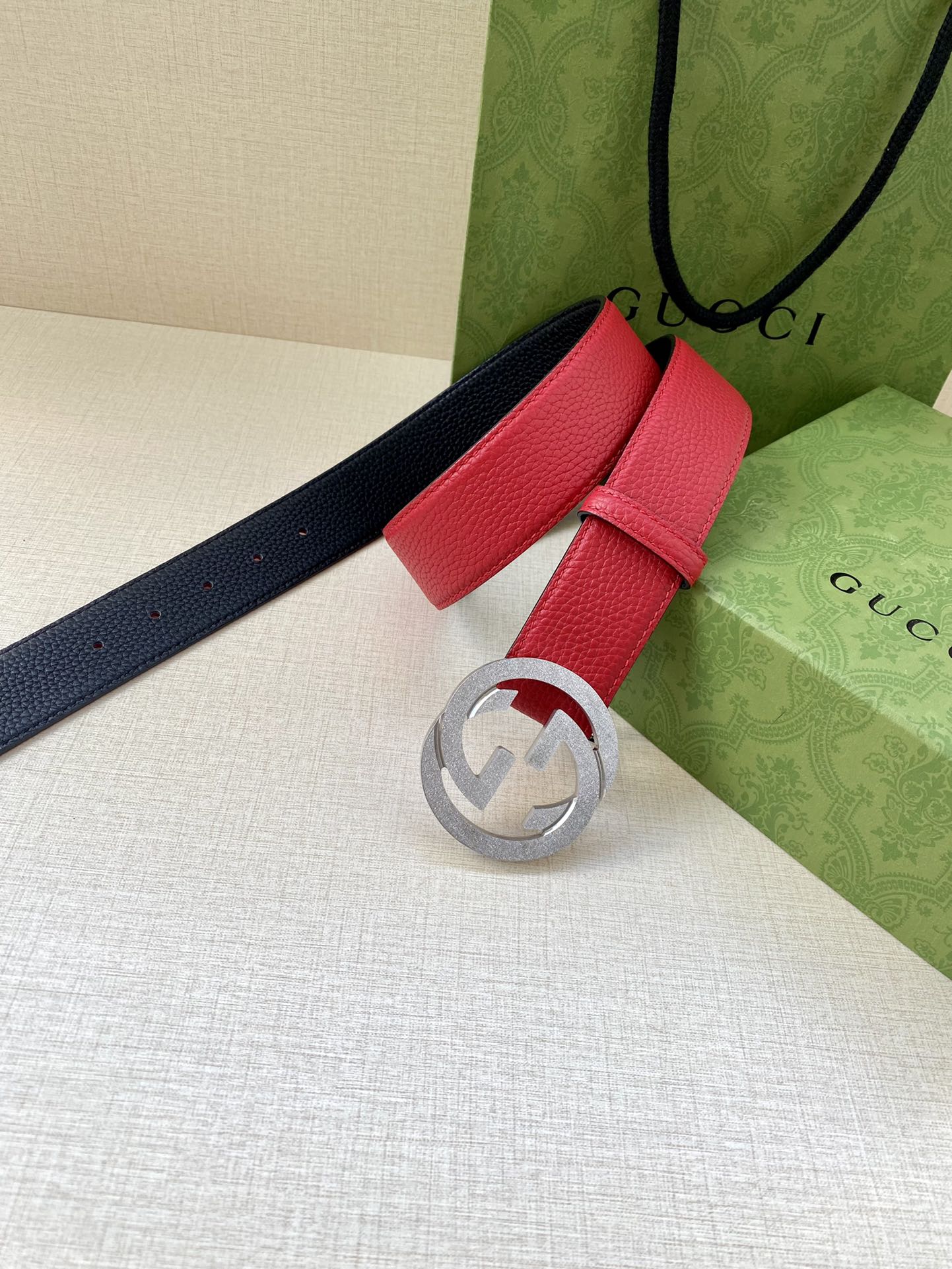 Red leather belt with silver-tone interlocking G buckle, paired with navy strap