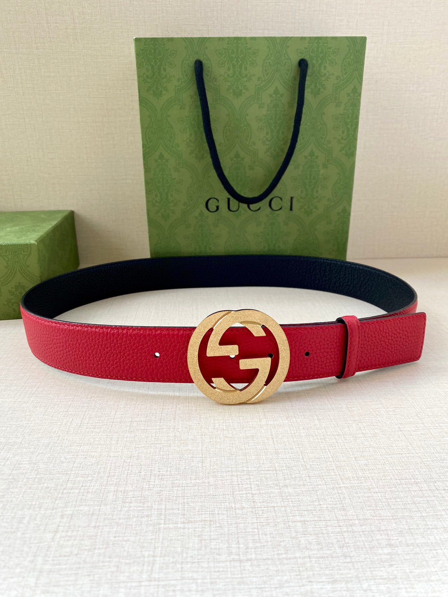 Red leather belt with gold-tone interlocking G buckle on navy-backed strap