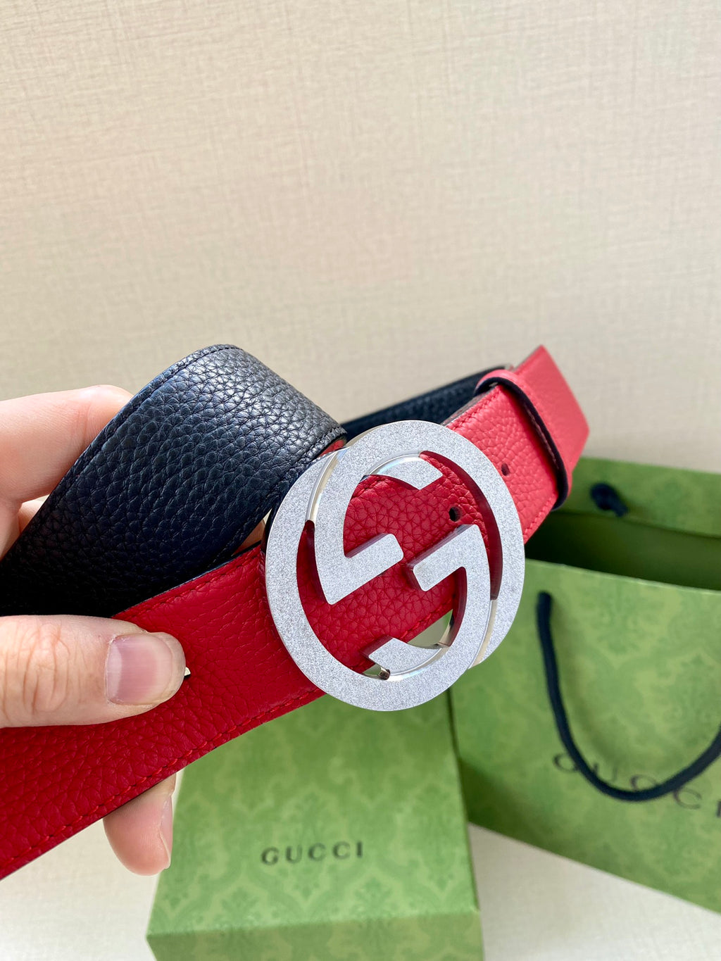 Close-up red leather belt with silver-tone interlocking G buckle and small holes