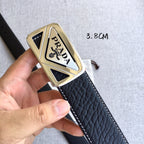 Prada belt buckle close-up on dark strap with gold-toned triangular metal frame