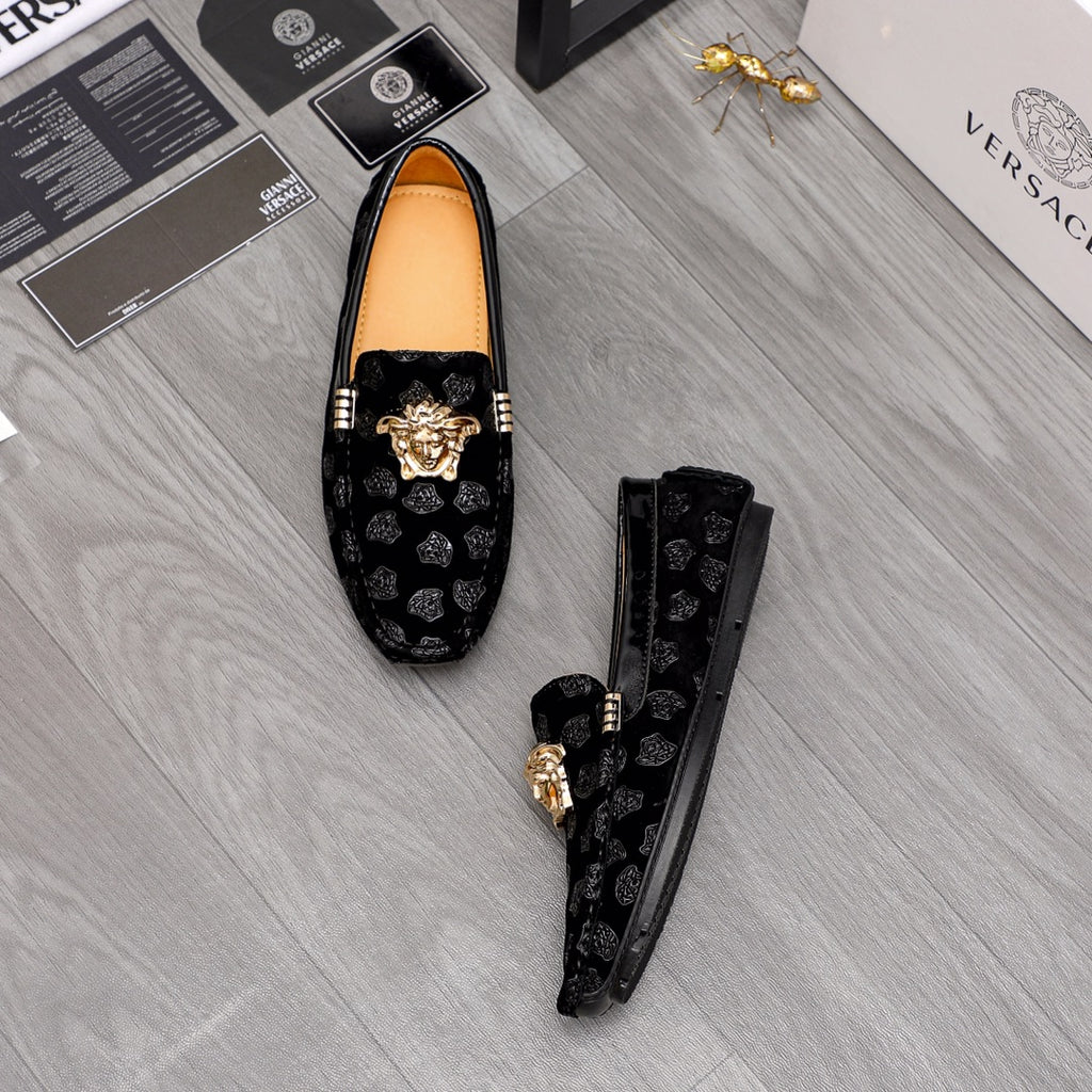 Black luxury loafers with gold Medusa emblem on patterned fabric and tan lining