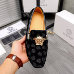 Black luxury loafers front view with gold Medusa emblem, patterned upper, tan lining