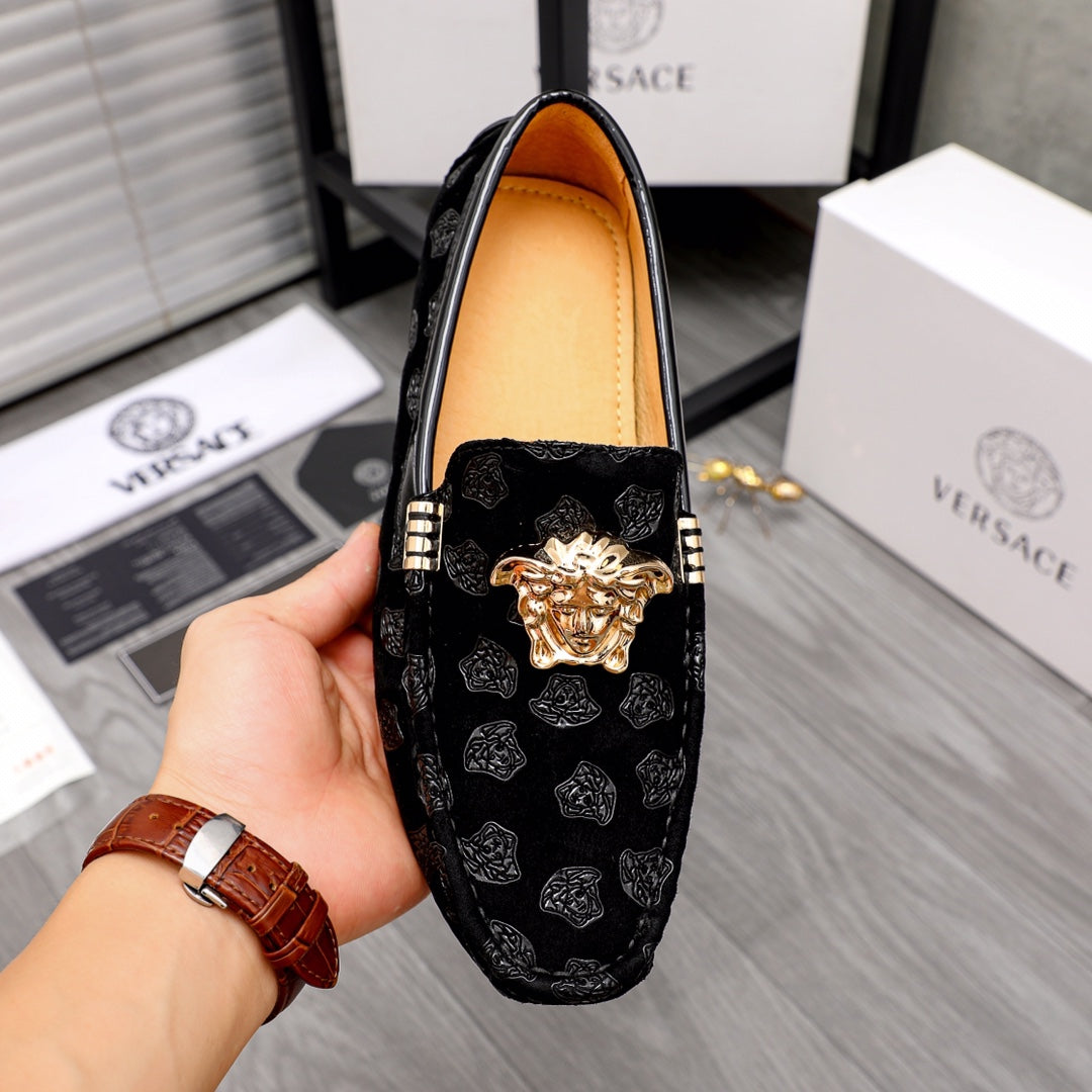 Black luxury loafers front view with gold Medusa emblem, patterned upper, tan lining