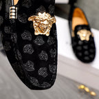 Close-up black luxury loafer with gold Medusa emblem on patterned textured upper