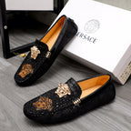 Black slip-on loafer pair with gold Medusa head hardware and embossed decor